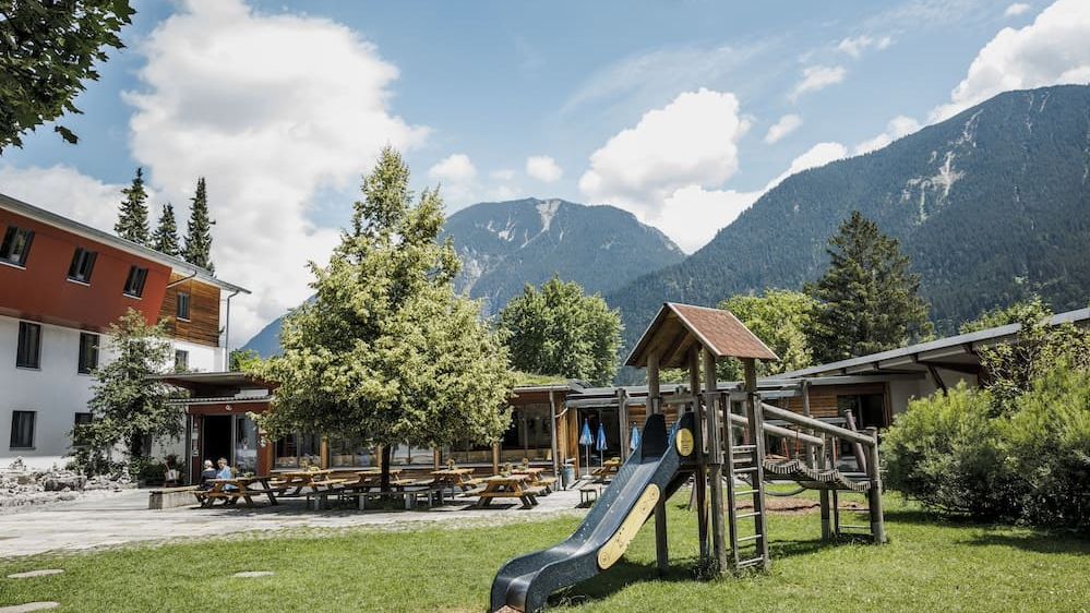 Panoramabild der Jugendherberge Garmisch mit Bergen und Spielplatz