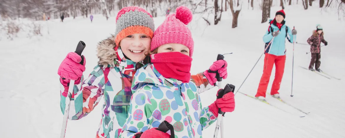 little girls cross-country skiing in the winter forest in the snow